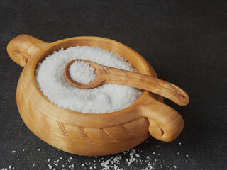 salt in a wooden cup with a spoon on the stone countertop