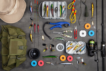 Fishing tackle - fishing spinning rod, hooks and lures on gray background. Active hobby recreation...