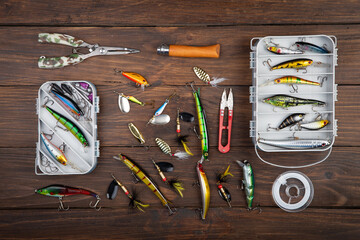 Fishing tackle - fishing spinning rod, hooks and lures on wooden background. Active hobby...