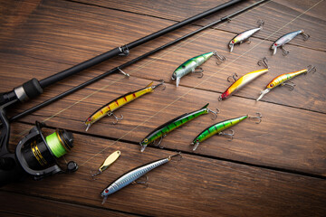 Fishing tackle - fishing spinning rod, hooks and lures on wooden background. Active hobby recreation concept.