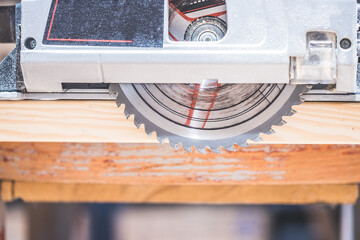 Sawing wood in the garage: Home handyman sawing plank of wood with circular saw