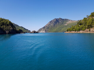 Fototapeta premium Seascape against the backdrop of mountains on a cloudless sunny day.