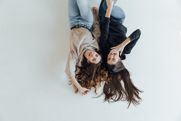 Top view of two happy smiling women lying in white background and looking at the camera