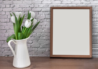 Portrait white picture frame mockup on vintage table with tulips jug vase grey white brick wall background.