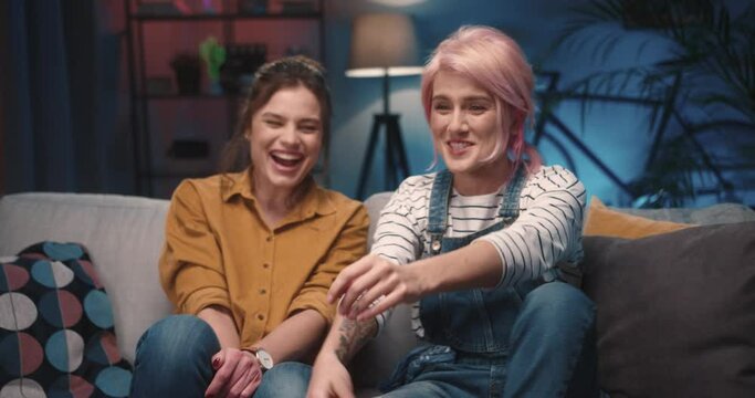 Close up of happy young Caucasian pretty women friends watching movie on TV having emotional reaction. Females watch sport channel on television supporting fav team, match, entertainment, leisure