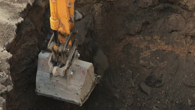 Big metal excavator bucket scoops up ground . Ripper bucket excavating soil and rocks at a construction site . Close up bulldozer digging building foundation in slow motion. Tractor working 