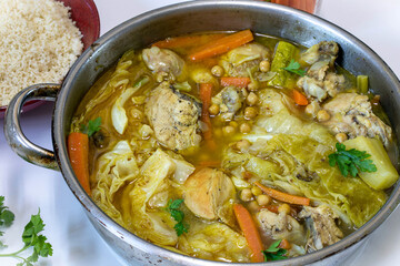 Stewed chicken with vegetables and hummus in a large iron saucepan.