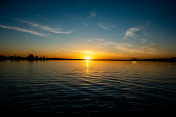 An early summer sunset over a lake in a small town in southern Russia, the sun is reflected in the water. 