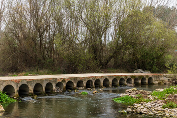 Bridge with small arches over the Serpis river next to the old train track.