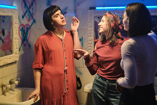 Transgender in dress smoking a cigarette and talking to the girls in the smoking room