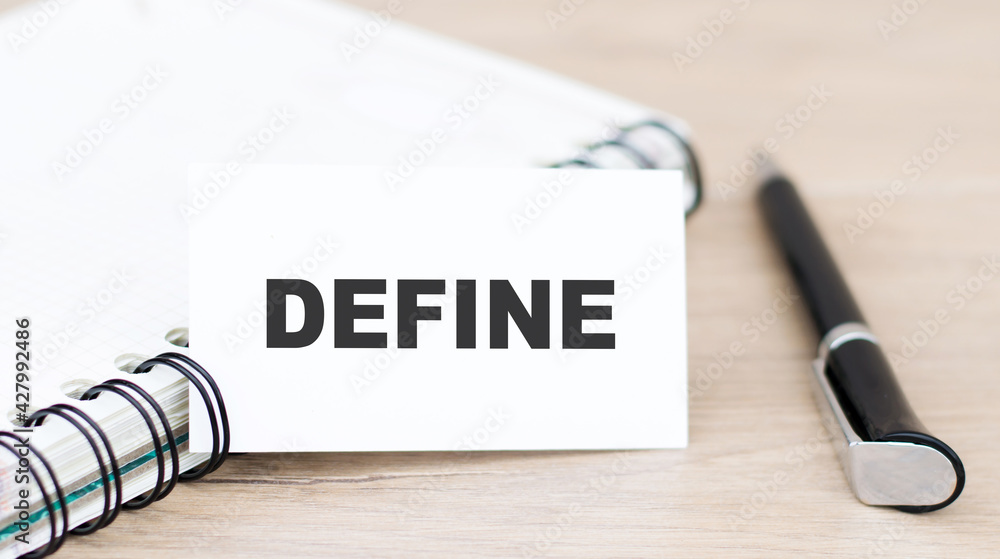 Poster define word on the card on a wooden table next to a black pen and notepad