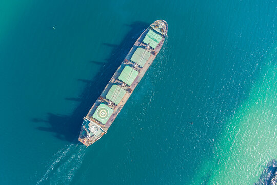 The Dry Cargo Vessel Enters The Port With The Help Of Tugs. Photo From A Helicopter. Bird's-eye View.