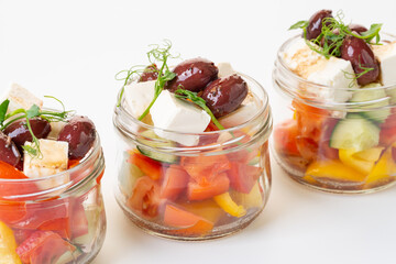 Vegetable salad with cheese in glass jars. Greek salad. Salads to take away. On a white background. Isolate. Catering services