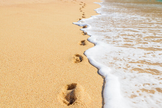 Footprints on the beautiful ocean sand. Set of pictures showing ocean waves in different stages over footprints. Cabo San Lucas. Mexico.