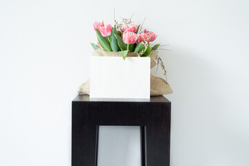 Blank paper greeting card, invitation. Bouquet of fresh pink tulips wrapped in burlap fabric...