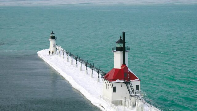 Aerial 4k shot of Frozen Lake Michigan Lighthouse and Pier. Location St. Joseph Michigan.