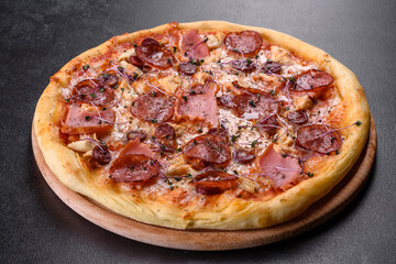 Delicious fresh oven pizza with tomatoes, salami and bacon on a dark concrete background