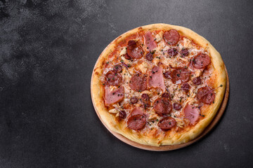 Delicious fresh oven pizza with tomatoes, salami and bacon on a dark concrete background