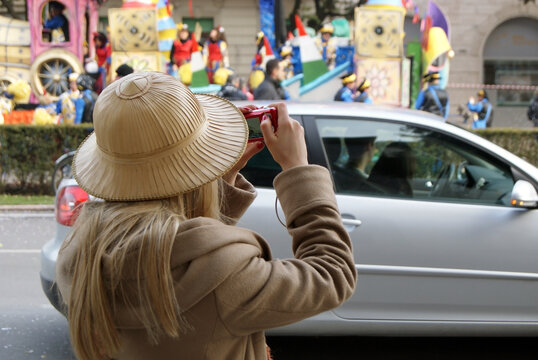 Blonde tourist wearing a colonial hat during the carnival.
Girl photographs the carnival floats in Verona during a parade.