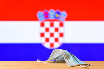 A medical mask lies on the table against the background of the flag of Croatia. The concept of a...