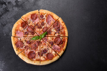 Delicious fresh oven pizza with tomatoes, salami and bacon on a dark concrete background