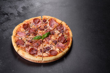 Delicious fresh oven pizza with tomatoes, salami and bacon on a dark concrete background