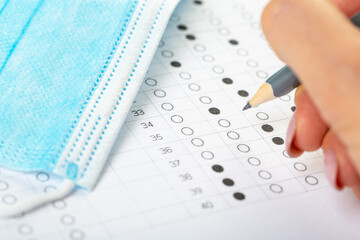 testing in exercise and examination work. blue medical mask, sheet with pencil in school test room, education concept during pandemic