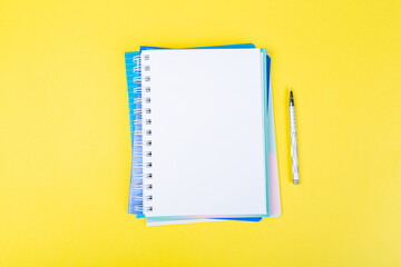 open spiral notepad on a yellow background with a pen. top view, stack of notepad with blank sheet. school concept, businessman work
