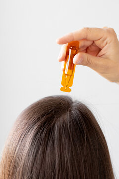 Caucasian woman holding an ampoule of vitamins and apply to the hair or skin, close-up, hair and skin oil, aminexil, hair restoration