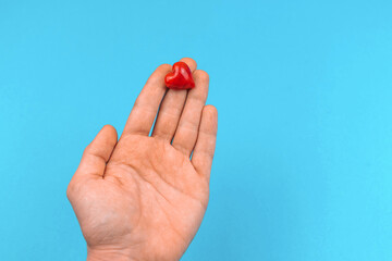 Man holding a small red heart in hand, donate and helping concept background, world heart and blood...