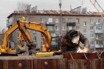 welder works at the construction of a residential building, monolithic construction, welding electrodes sparks monolith concrete, reinforcement builder engineer foundation, iron welding