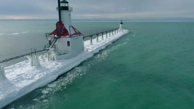 Aerial 4k shot of Frozen Lake Michigan Lighthouse and Pier. Location St. Joseph Michigan.