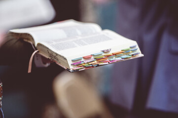 Hand holding an open Bible book with bookmarks