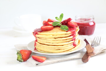 Pancakes with strawberries and mint on a white background