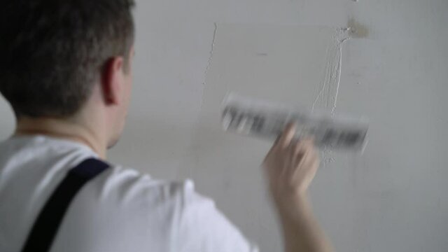 A construction worker builder makes repairs renovation in an apartment or building. Put on a putty, leveling the walls High quality 4k footage