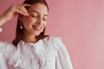 Happy smiling elegant model with flawless skin wearing trendy pearl earrings, vintage blouse with cotton lace collar, posing on pink background. Close up portrait. Copy, empty space for text
