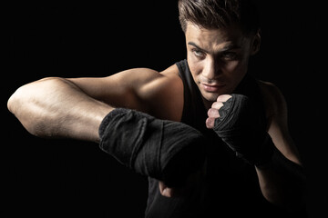 Fototapeta na wymiar Portrait of young sportsman in boxing wraps posing in boxing stance