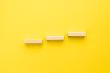 stairs made by wooden bricks over yellow background. above view. abstract creative staircase....