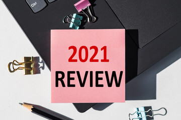 2021 REVIEW text on a small piece of paper. Concept photo - summary of the year 2021
