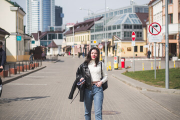 Beautiful young girl student hipster walks along the street of her city