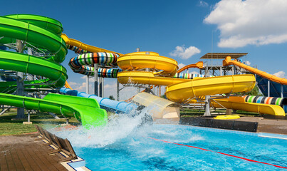 water park, bright multi-colored slides with a pool, a water park on a summer day