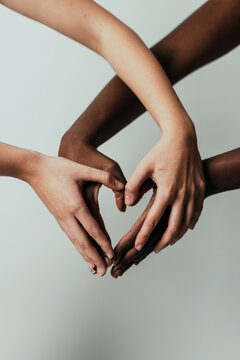 Cropped Hands Of Women Making Heart Shape Against Gray Background