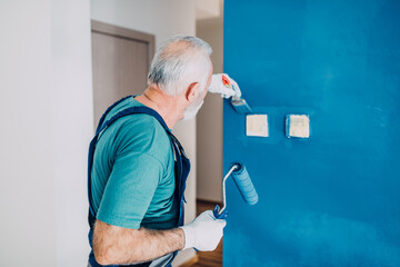 Senior male painter painting a wall.