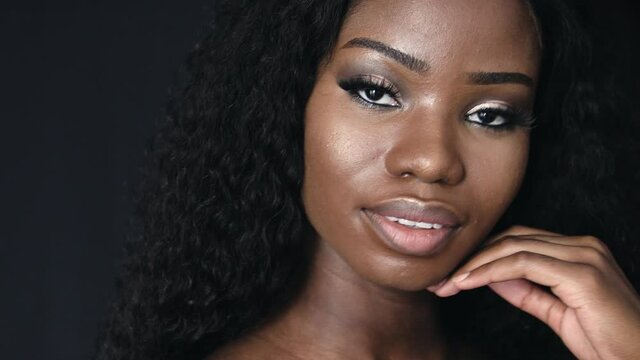 Attractive african model posing on camera on dark background, make up tips