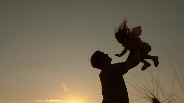 Best Dad throws his lucky daughter into sky. Silhouette Father and little child play, laugh, hug together. Child plays and wants to fly like an airplane. Family travel. Family walking in park, summer