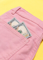Two new banknotes of one hundreds dollars in pocket of pink pants.