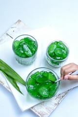 Manisan Kolang Kaling, or preserved sugar palm fruit, tinted green, served in bowl and glasses. 