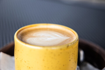 Yellow cup of cappuccino foam art