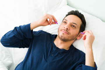 Good-looking man using ear plugs to fall asleep