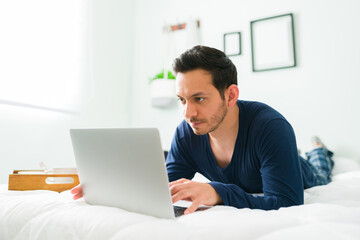 Hispanic man in pajamas online shopping on a laptop